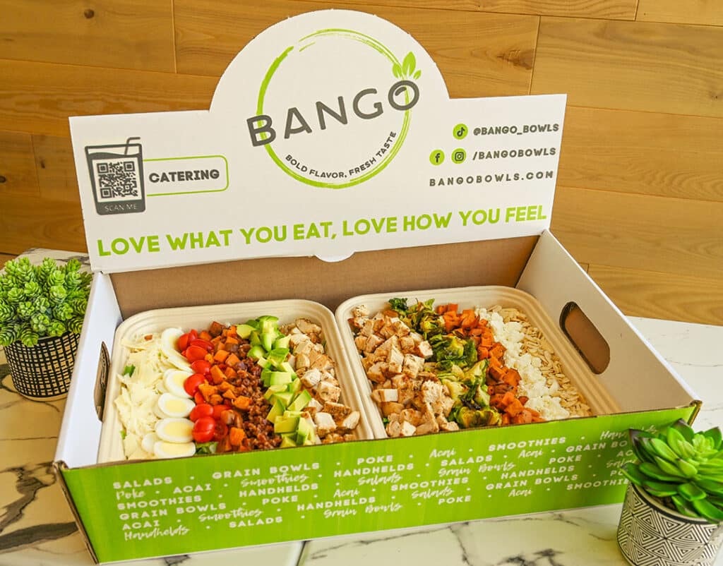 Bango Bowls catering box with two trays of fresh salads featuring chicken, avocado, sweet potatoes, eggs, and toppings